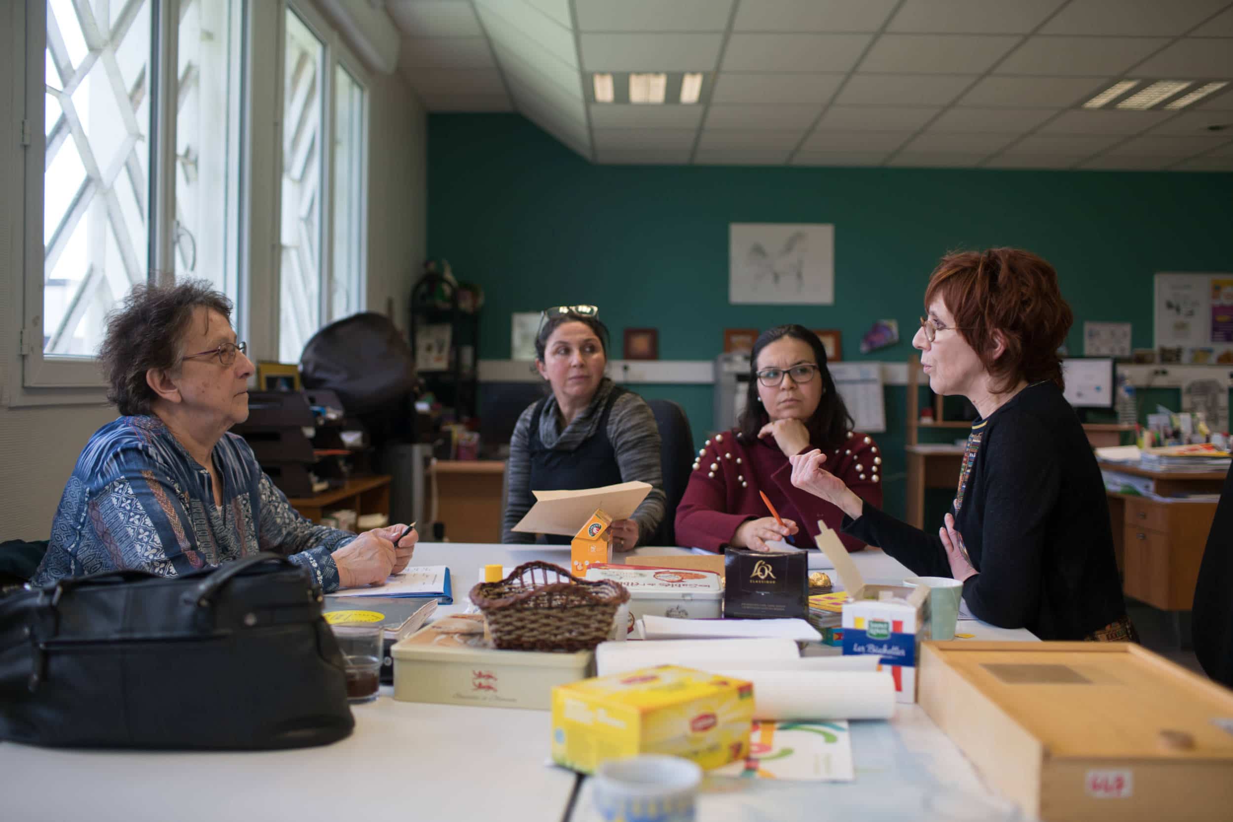 Lors d'une réunion autour d'une table, Iabelle s'adresse à trois de ses collègues de travail