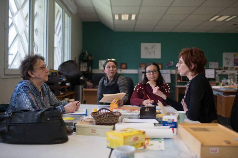 Lors d'une réunion autour d'une table, Iabelle s'adresse à trois de ses collègues de travail