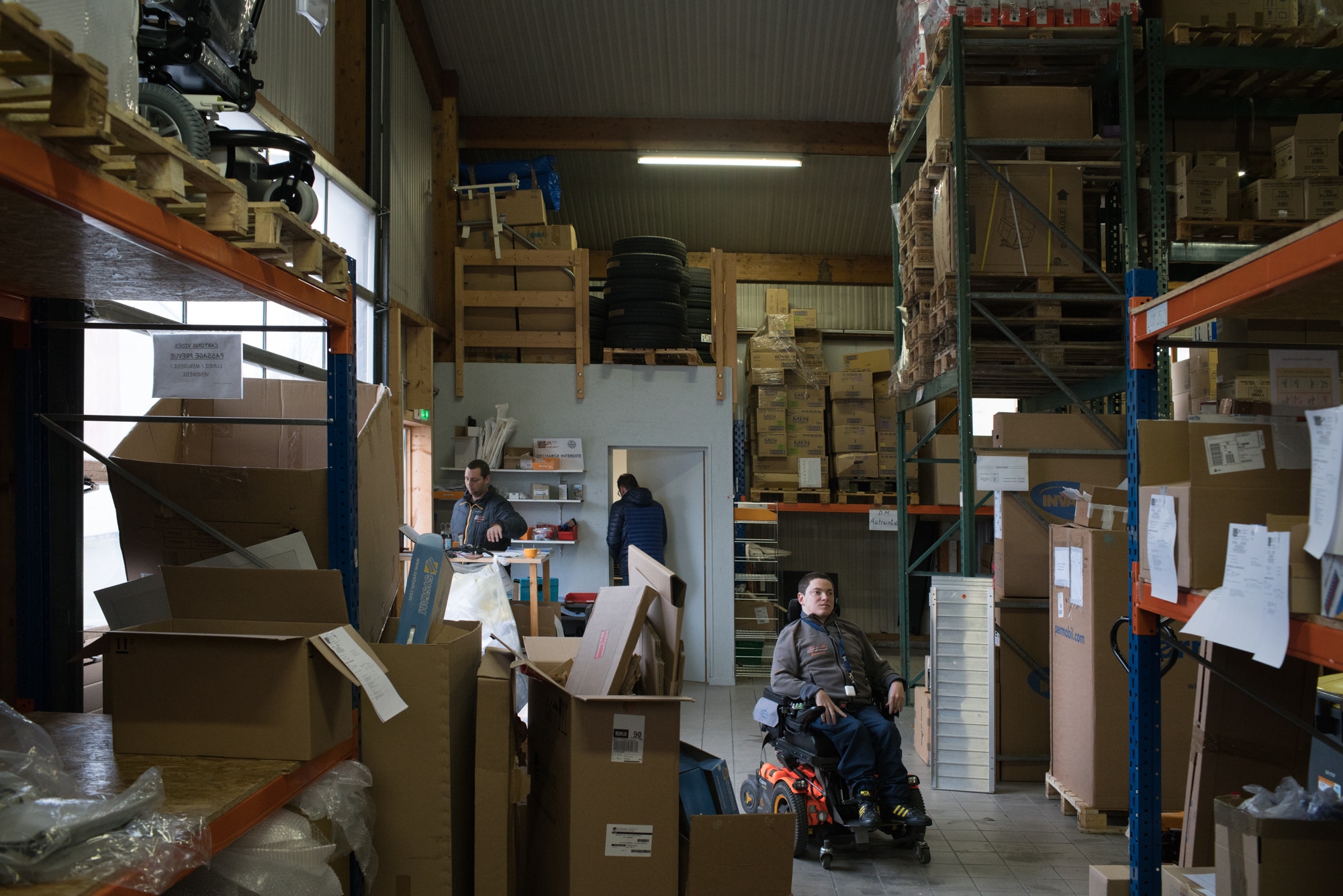 Un plan large présentant Edouard dans un grand entrepôt contenant palettes et cartons