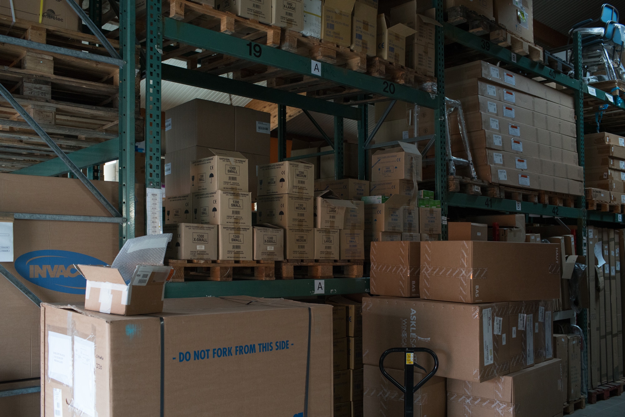 Un coin de l'entrepôt où s'empilent des cartons sur de grandes étagères