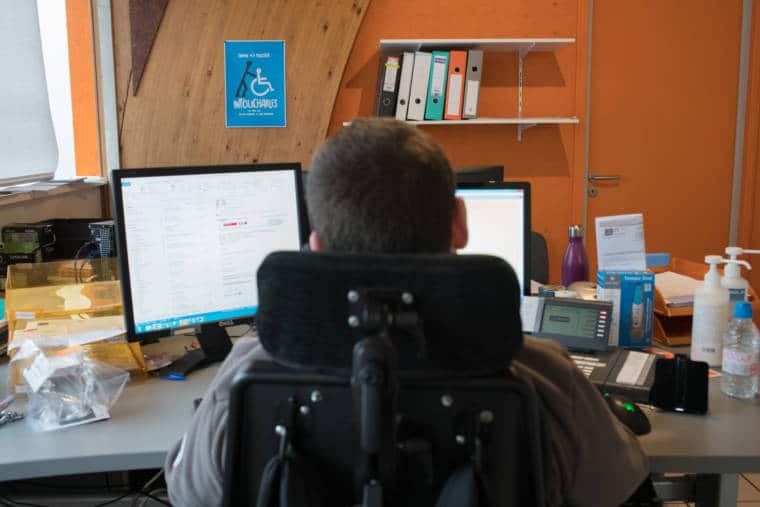 Edouard, vu de dos, travaille devant ses deux écrans d'ordinateur