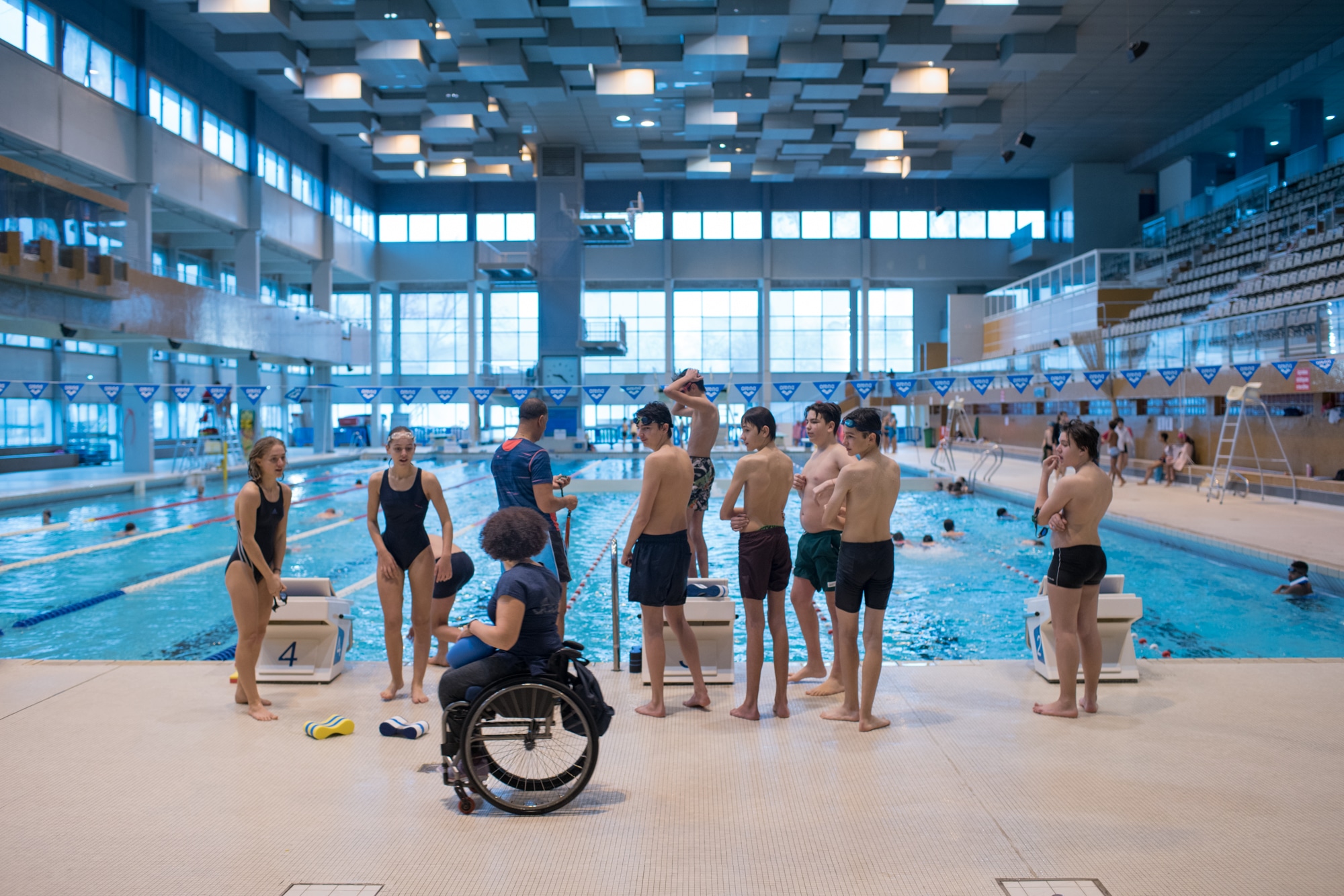 Hadda s'adresse à de jeunes nageurs dans une piscine municipale.