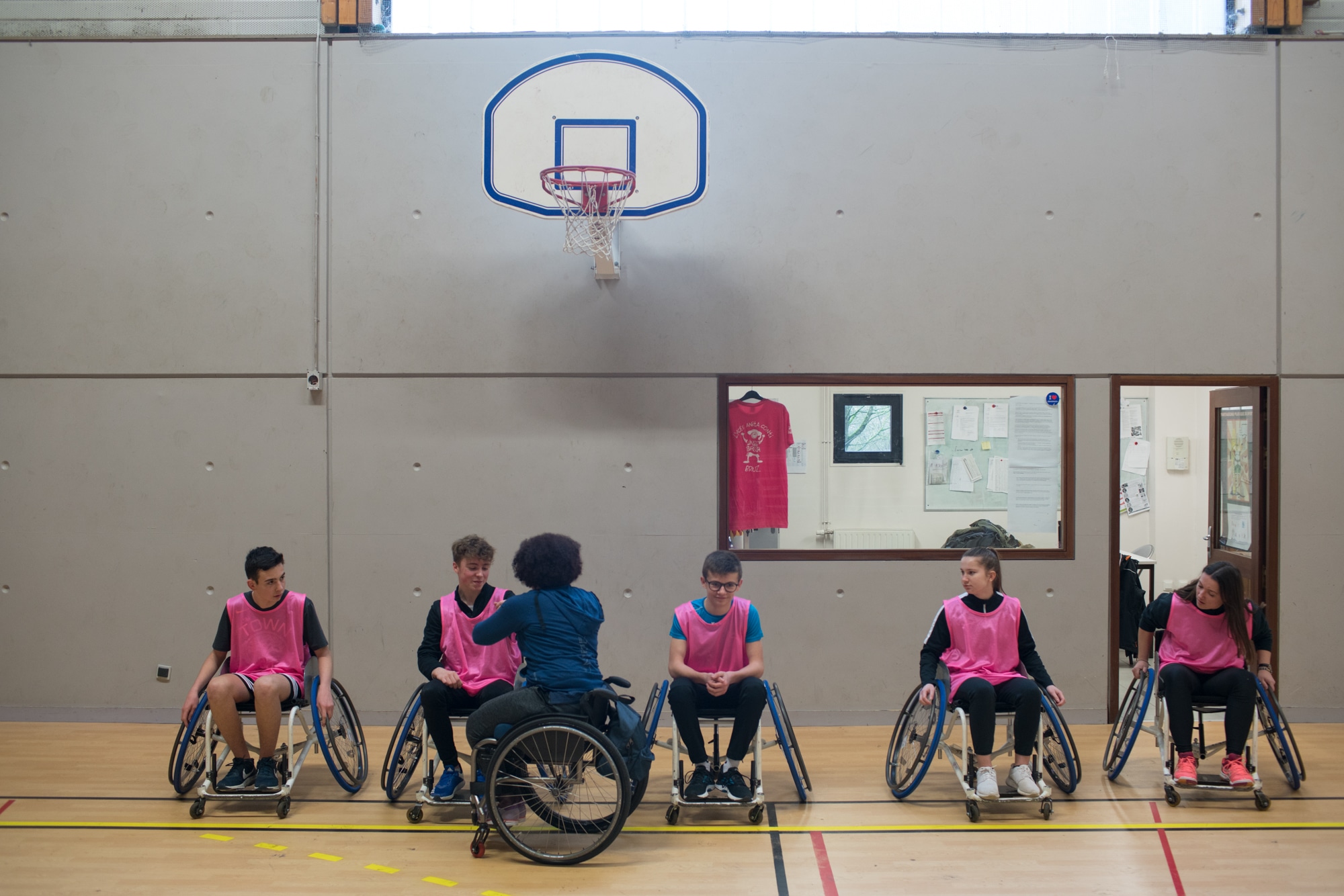 Les élèves d'Hadda sont alignés sous le panier de basket alors qu'Hadda s'adresse à eux.