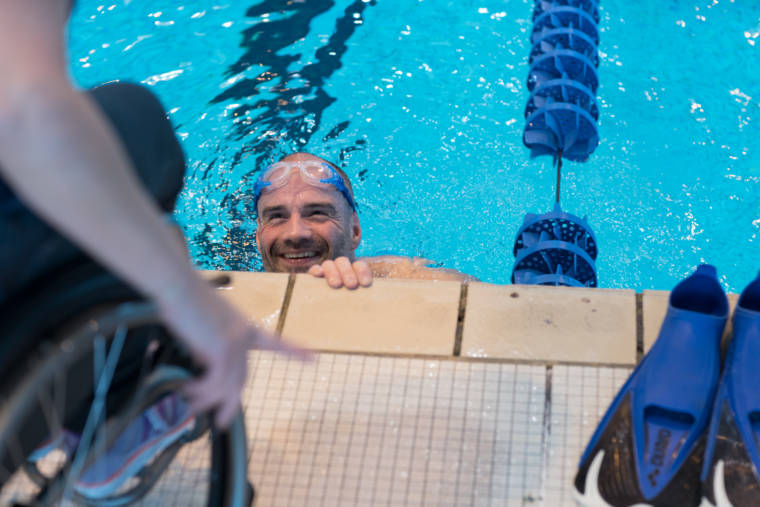 L'élève d'Hadda, dans la piscine, la regarde en souriant.