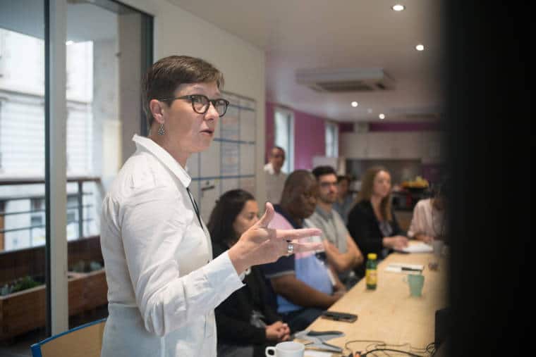 Mathilde se tourne vers l'écran en continuant sa présentation.