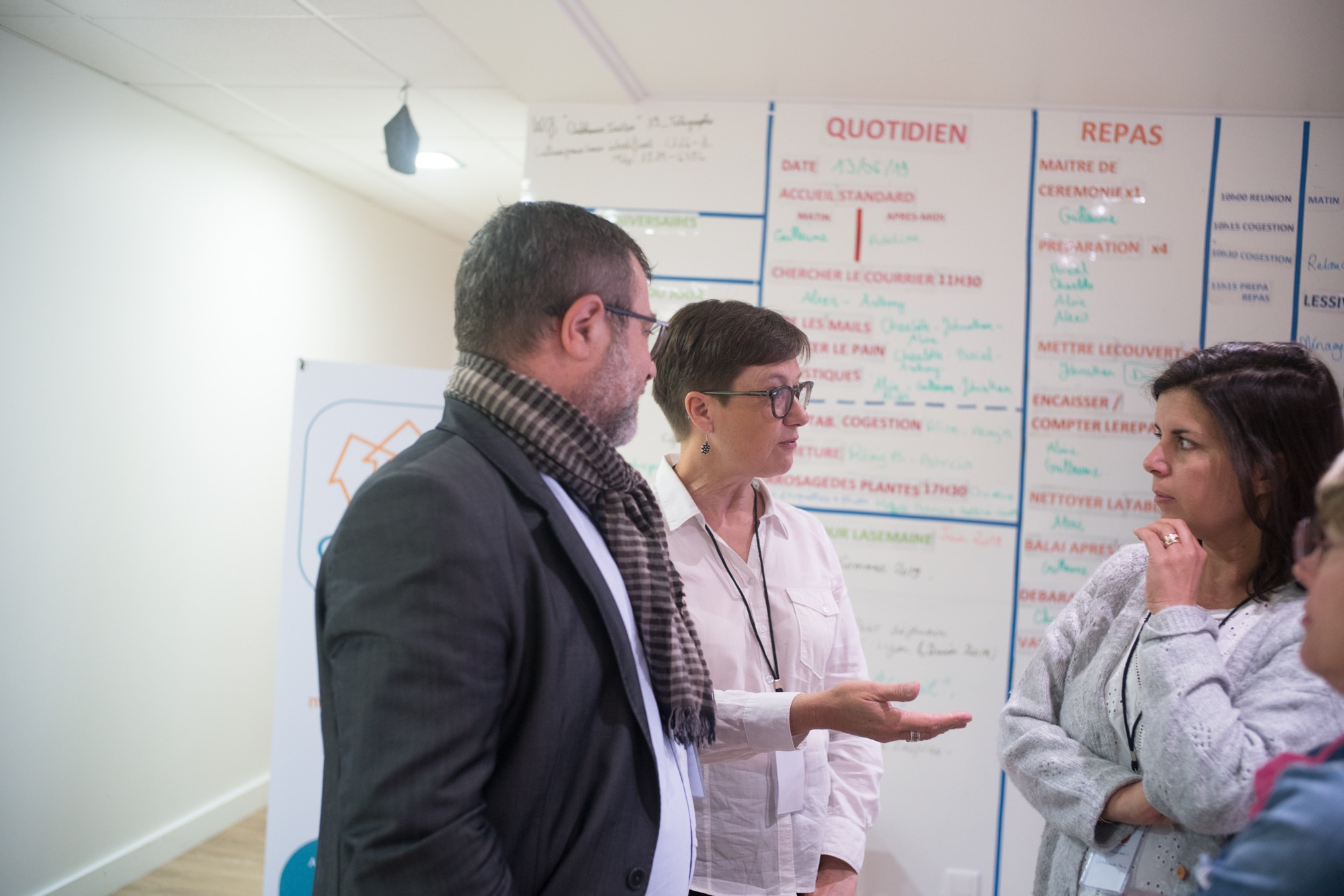 Mathilde discute avec deux personnes devant un tableau de tâches.