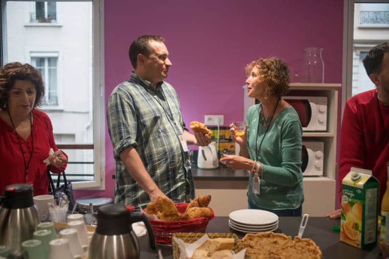 Plusieurs personnes discutent autour d'une table sur laquelle est disposé un petit-déjeuner.